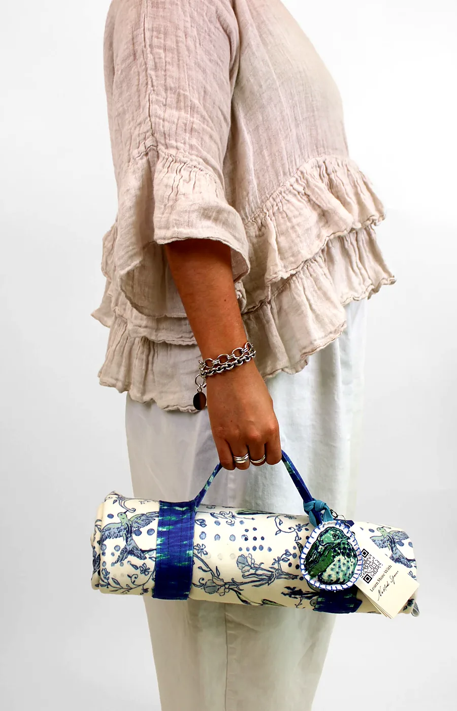 The Plumage throw rolled in its strap carry case, carried by hand